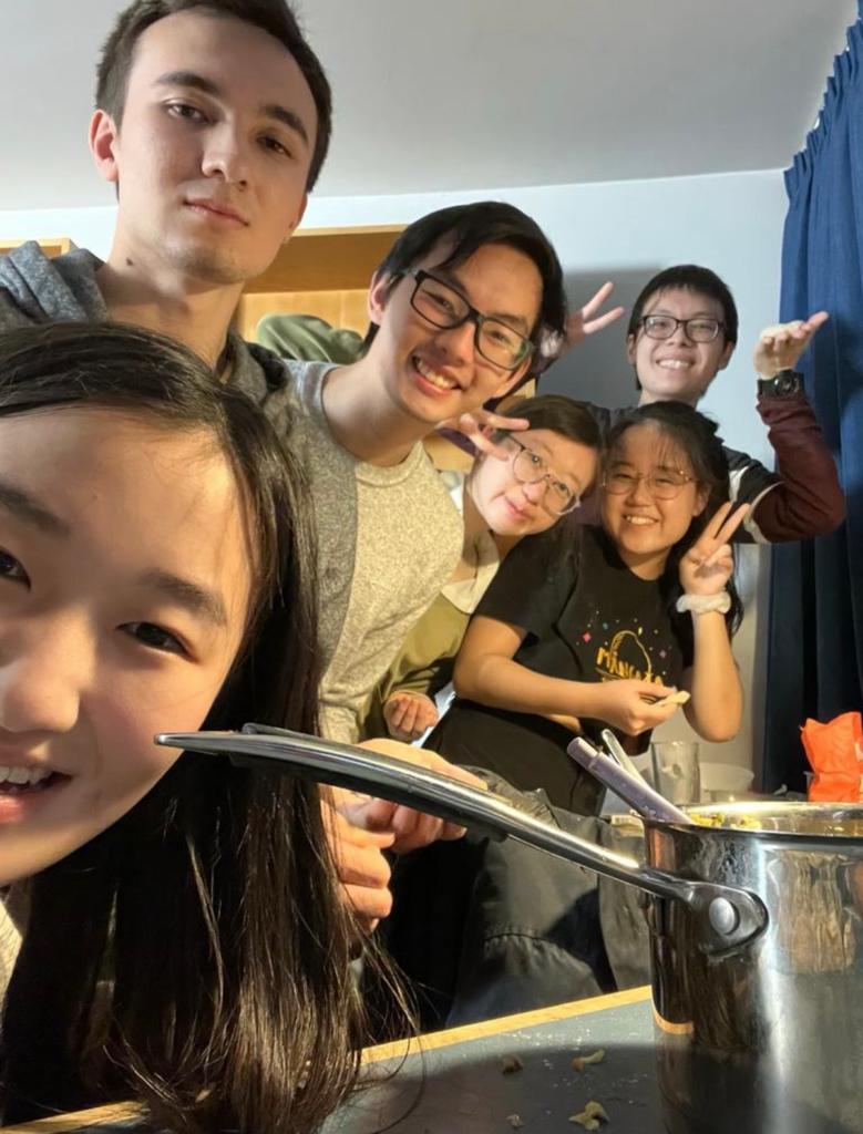 A selfie with pot of food cooking and Yii-ling in the foreground, and several other students in the background