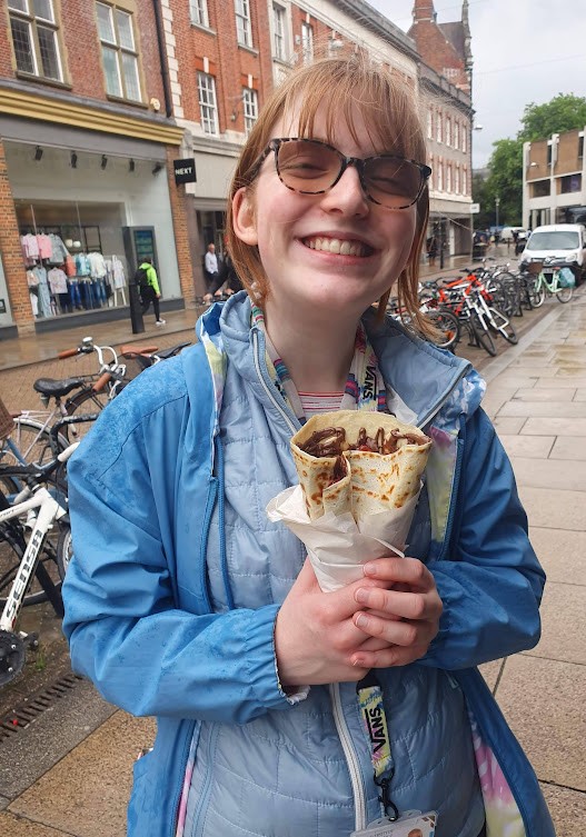 Sophie holding a chocolate crepe, smiling