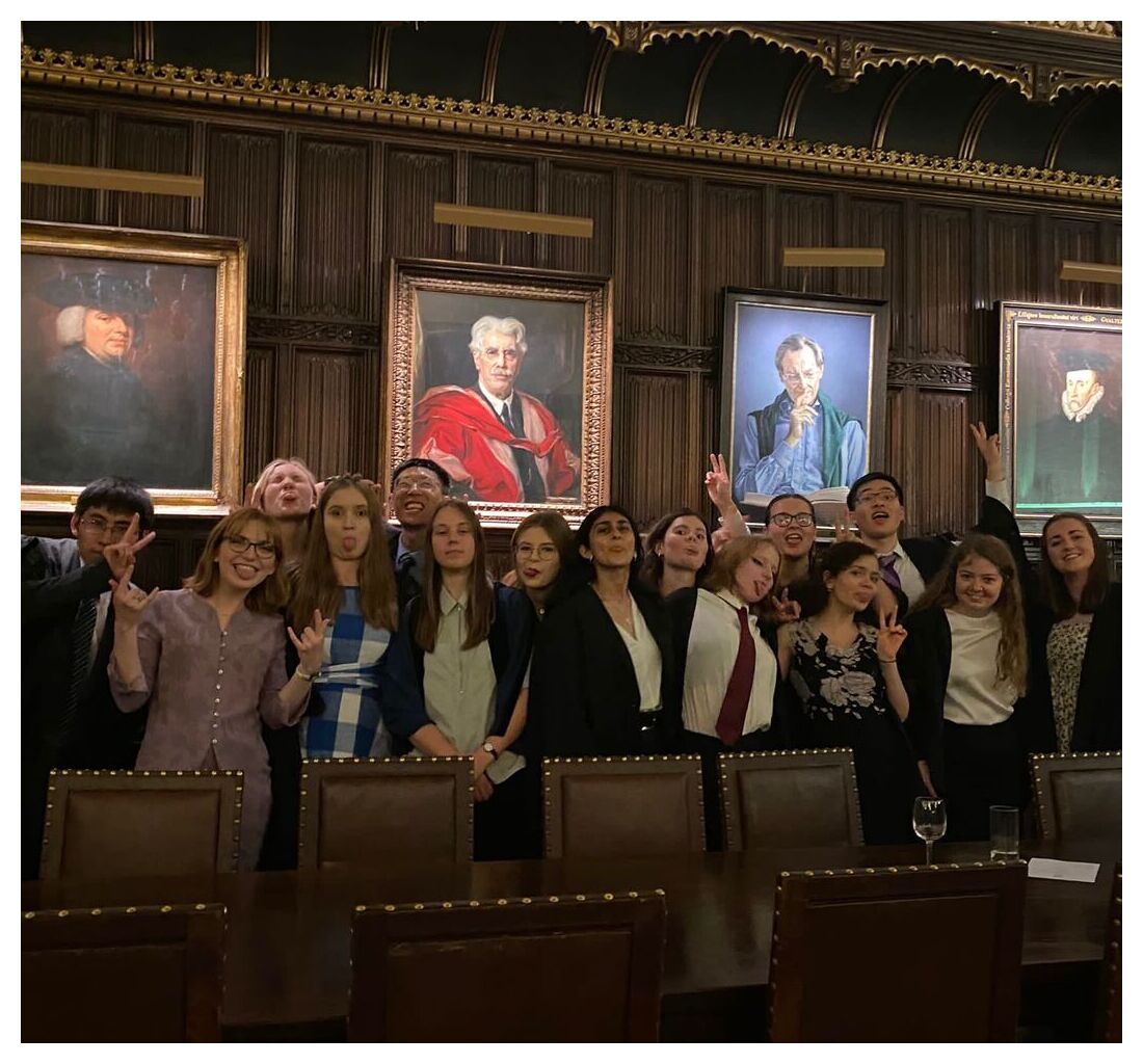 A large group of friends pilling faces, dressed in formal clothes in Formal hall