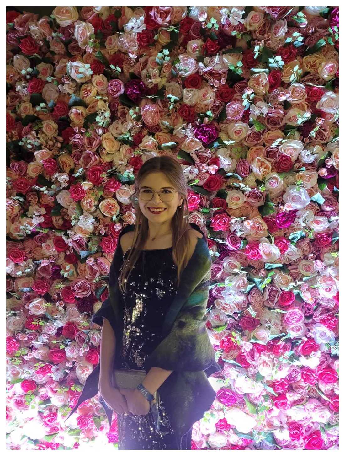 Oliwia in front of a wall of flowers