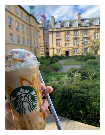 Starbucks cup, in front of buildings in Third Court