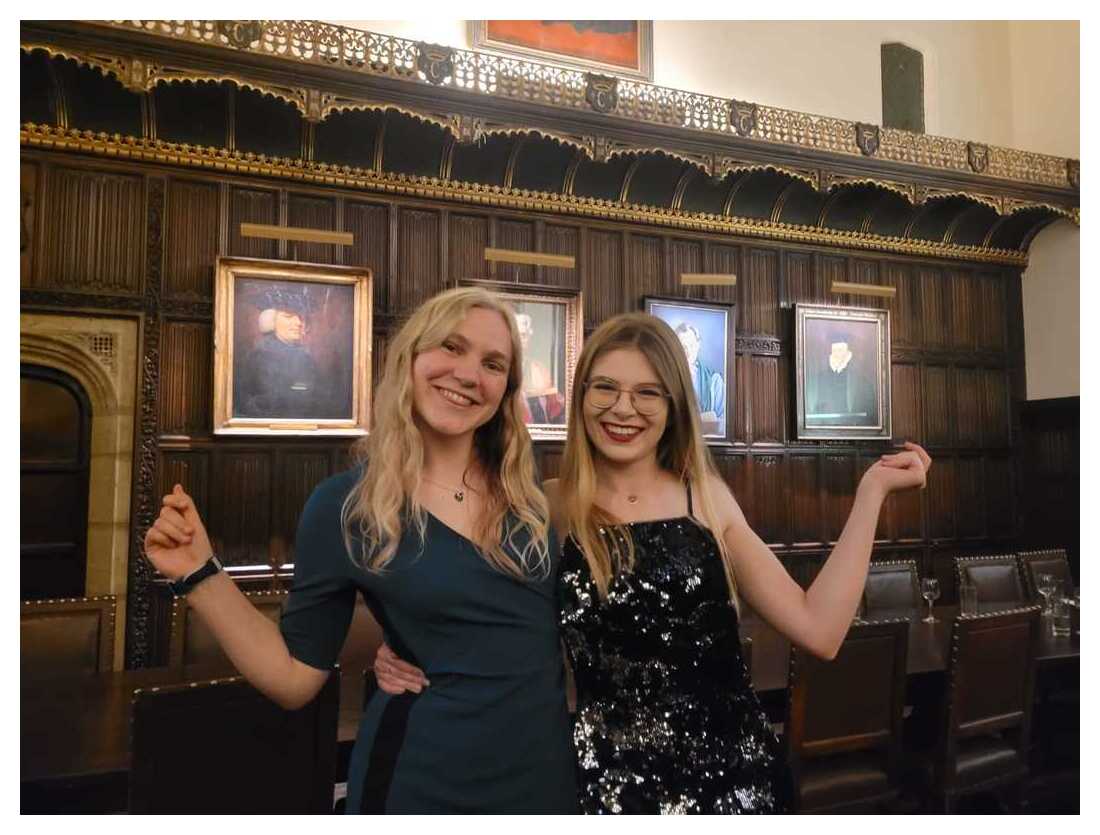 Two students doing a sassy pose, laughing, in Formal Hall