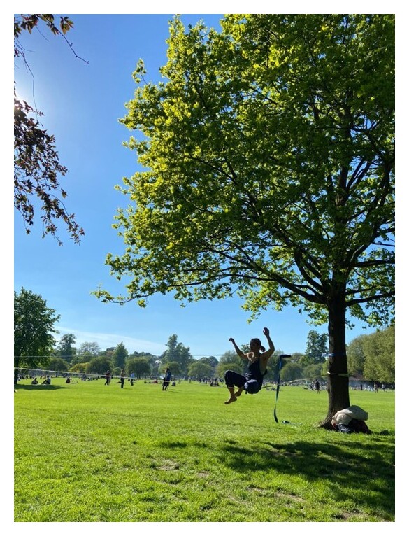 Ari on a slackline, with a park in the background