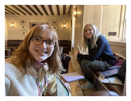 Two students with laptops and paper, sat in the College Buttery