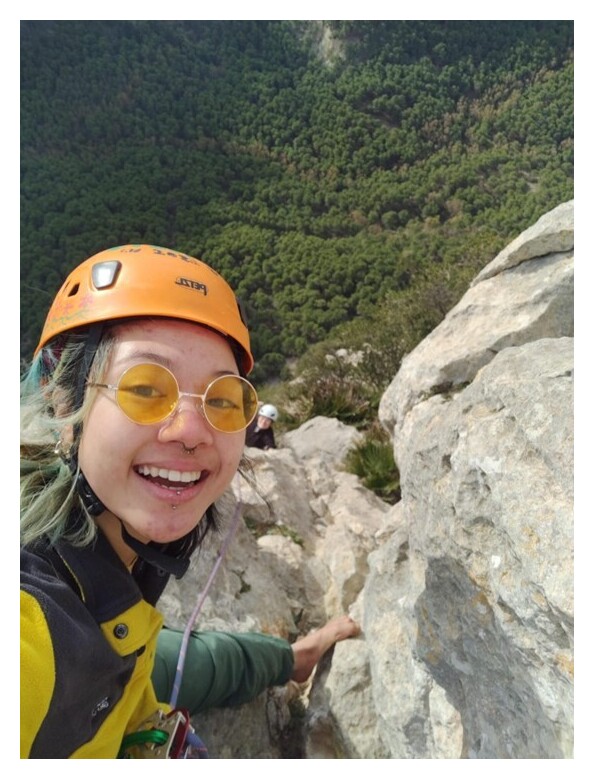 Selfie of Ari on top of a rock, in climbing gear