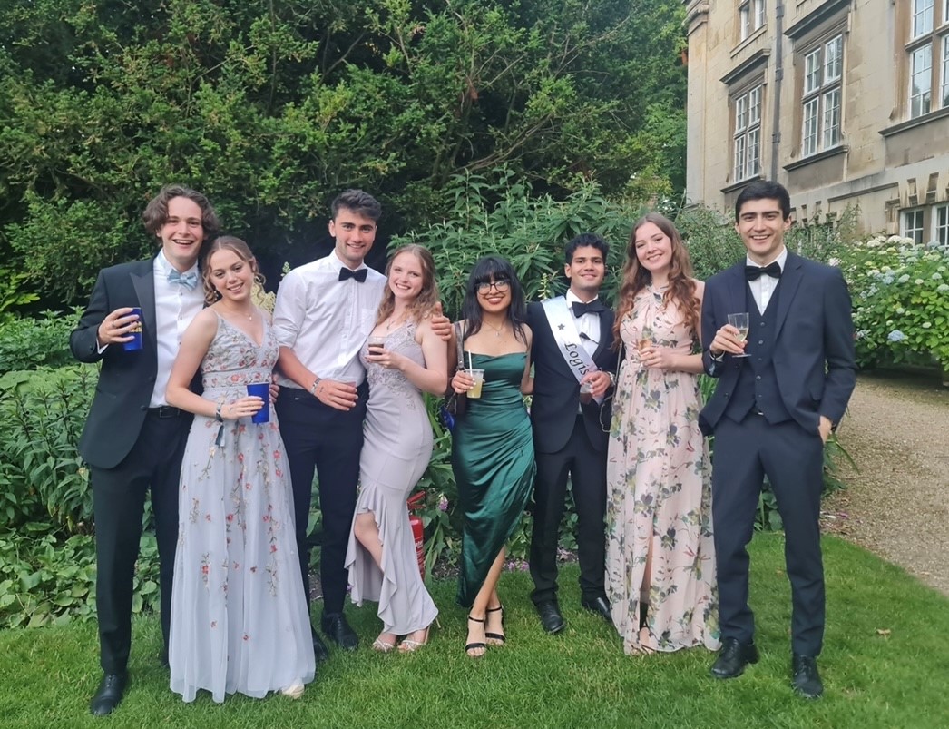 A group of people in formal outfits, stood in a pretty garden