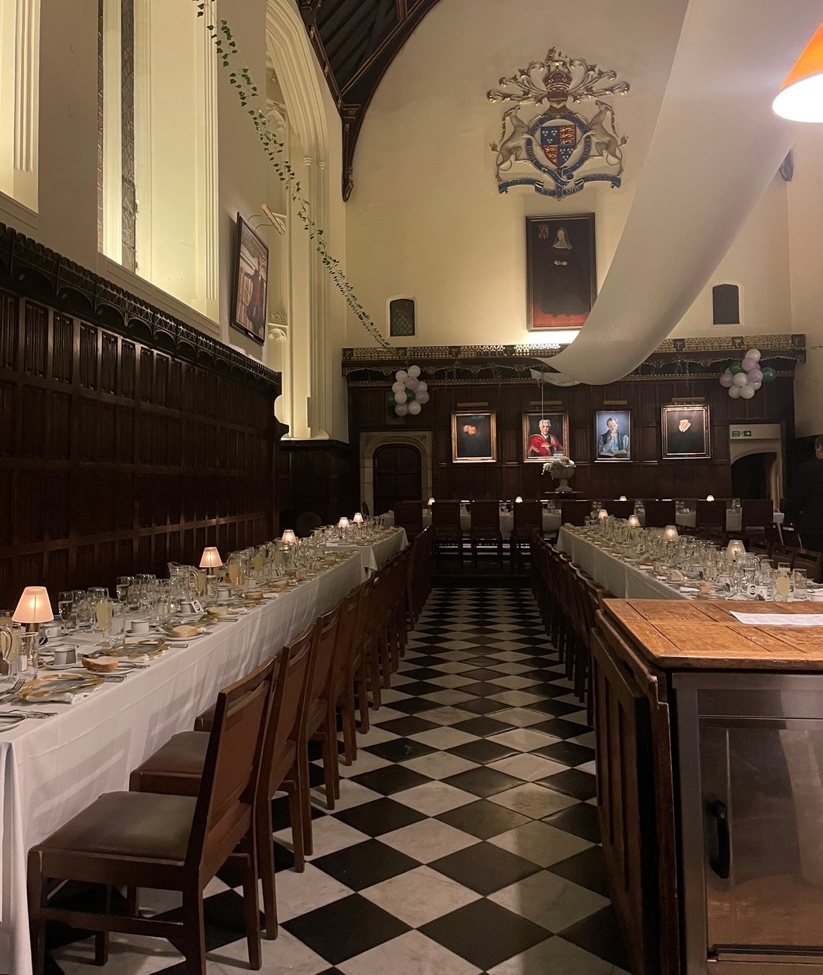 A formal dining hall, set with plates and glasses