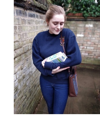 A woman holding a bottle of Alpro soya milk as though it were a baby, smiling at it affectionately.