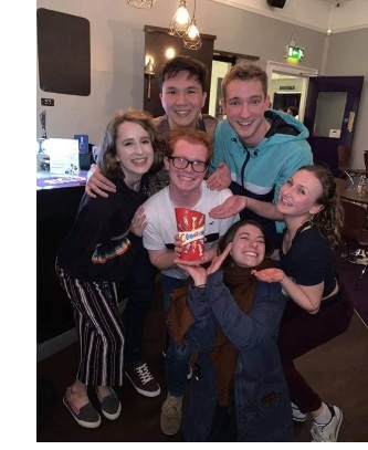 A group of students posing around, and holding, a tub of Celebrations.