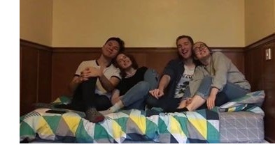 Four students, leaning on each other and laughing, sat on a bed in a student room at Christ's College, Cambridge.