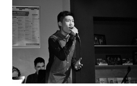 A black and white photo of a man singing in the bar of the ADC Theatre in Cambridge.