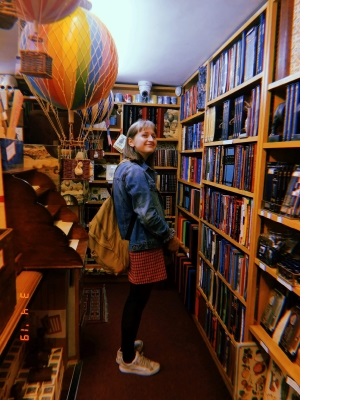 A woman, looking over her shoulder at the camera, in a bookshop.