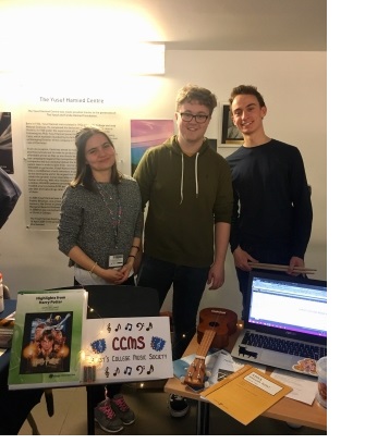 Three students standing in front of a stall during the Freshers Fair in the Yusuf Hamied Centre at Christ's College, Cambridge.