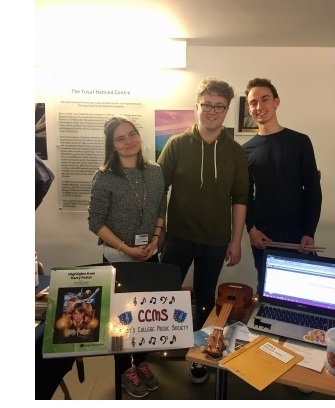 Three students standing in front of a stall during the Freshers Fair in the Yusuf Hamied Centre at Christ's College, Cambridge.