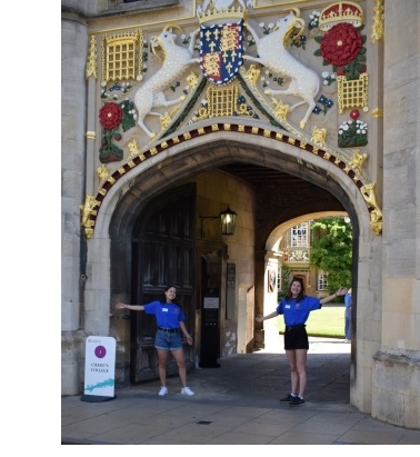 Two student helpers welcoming visitors to Christ's College during a summer Open Day at the University of Cambridge