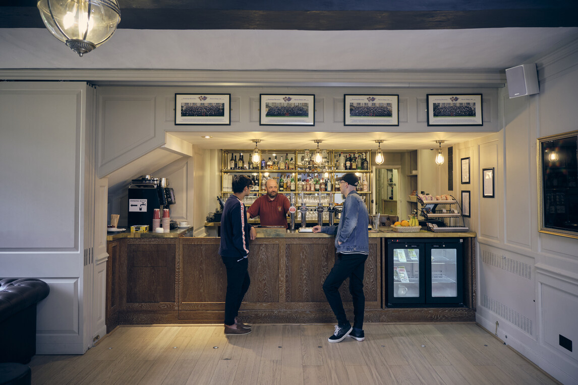 Two students chatting with bar staff member