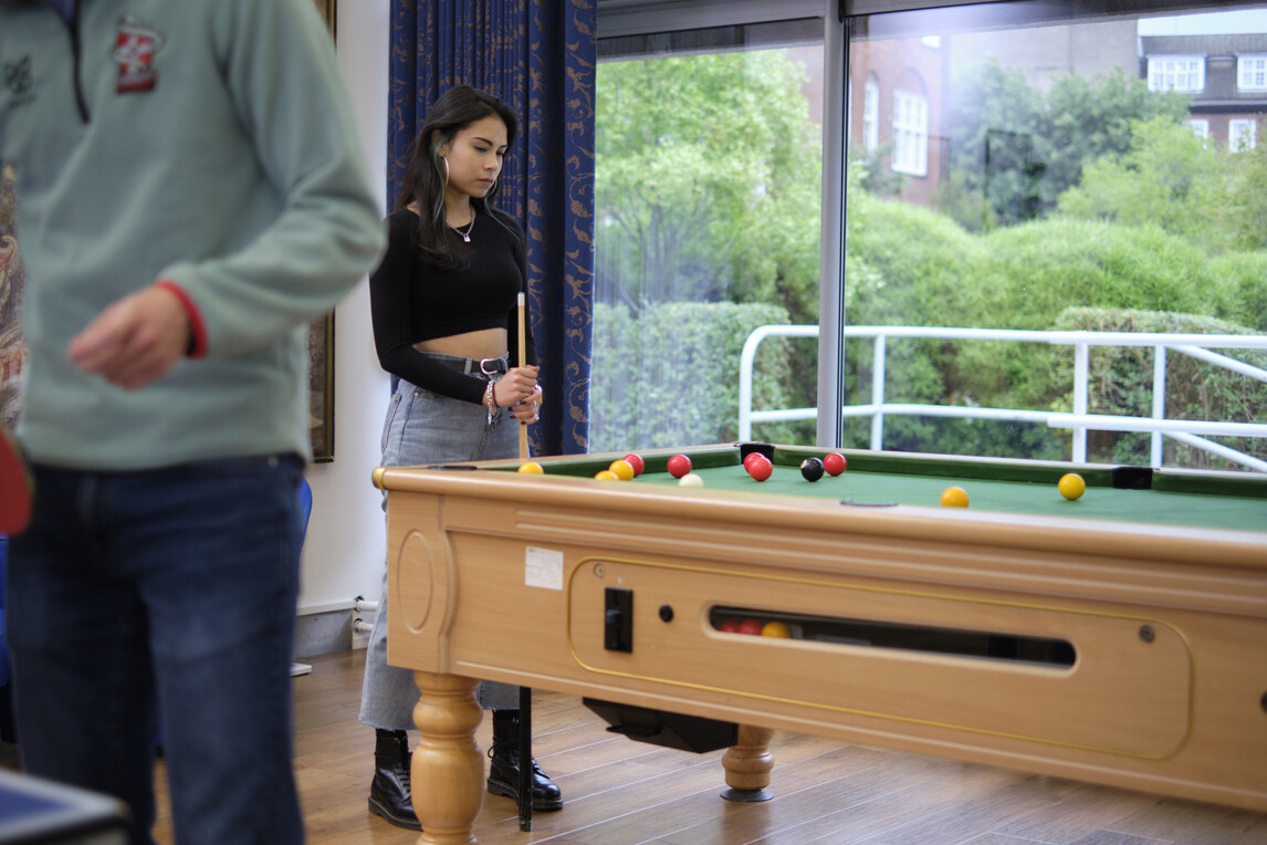 Female student standing by pool table