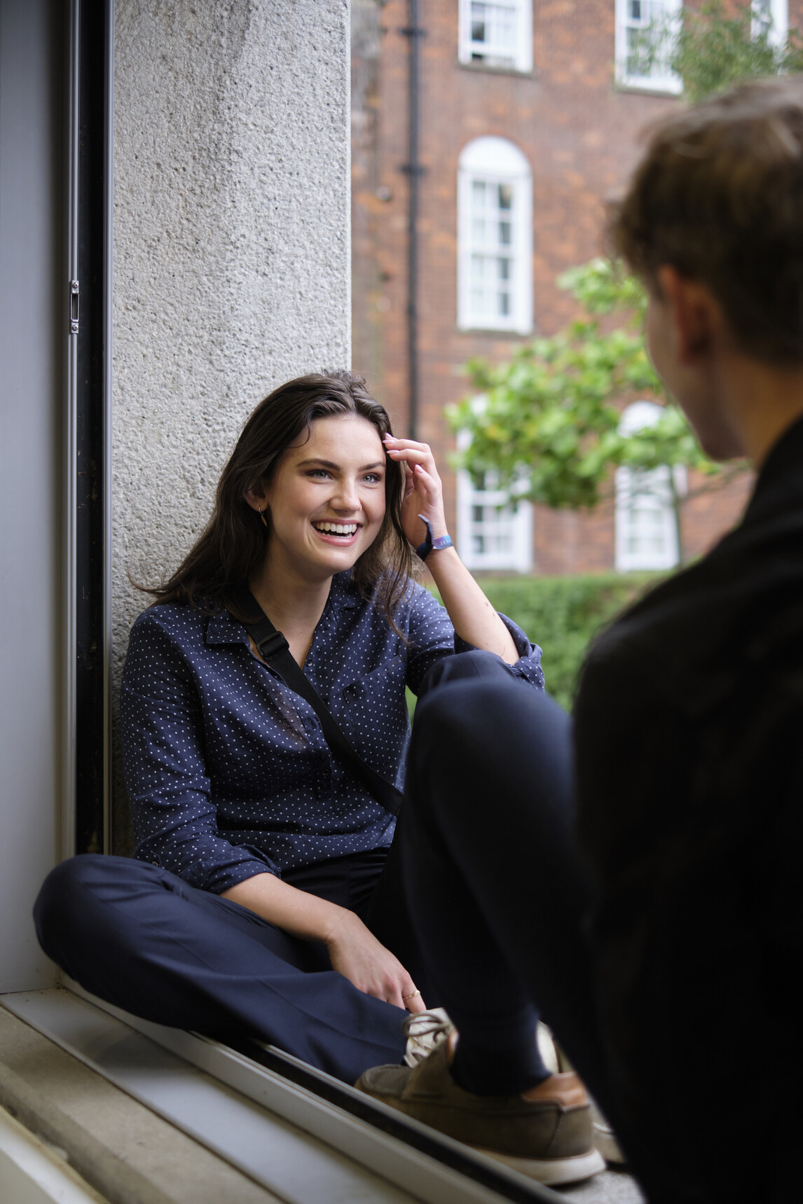 Female student sitting in window, laughing