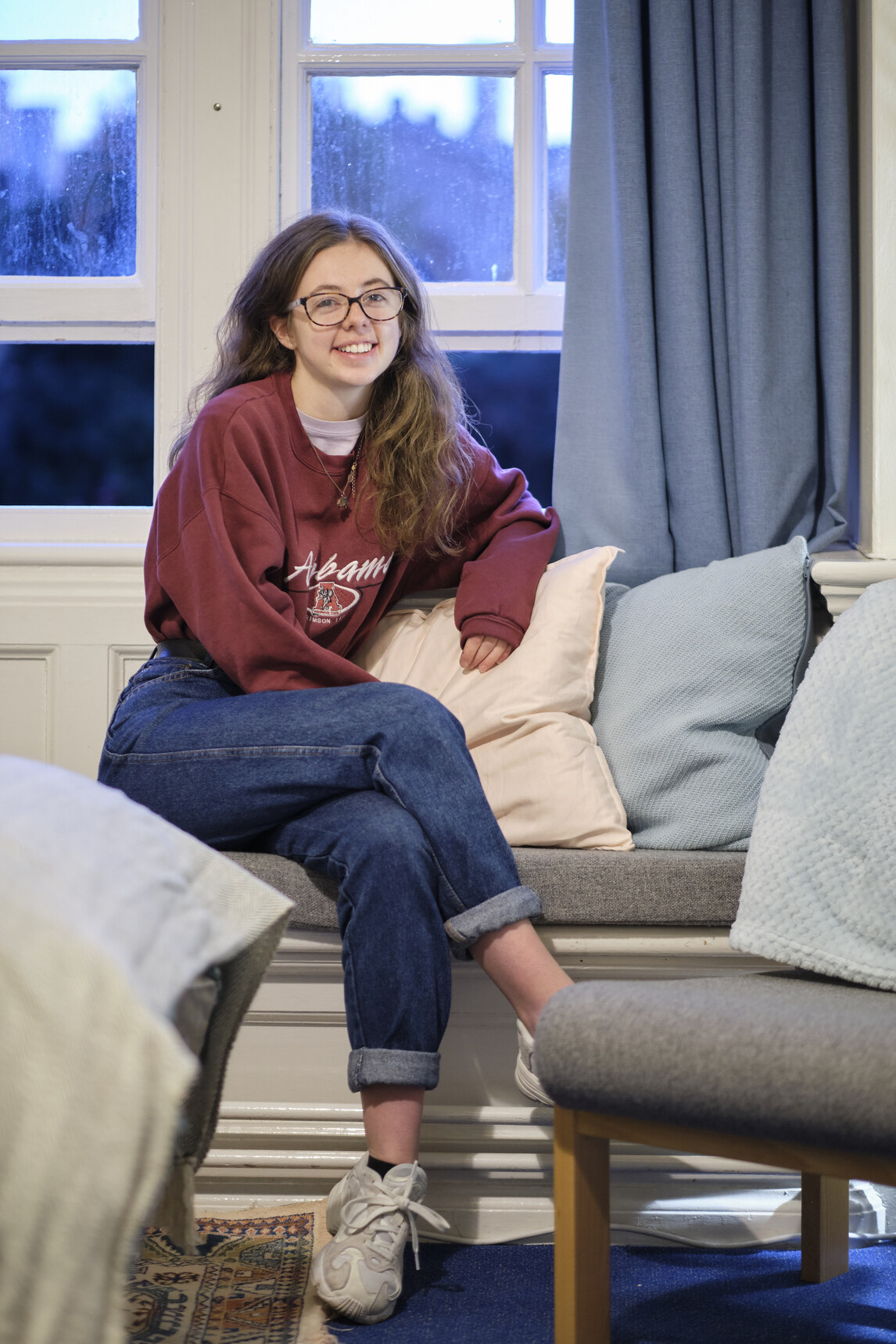 Student sat in bay window with cushions