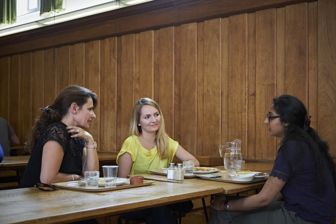 Three students chatting with empty food trays