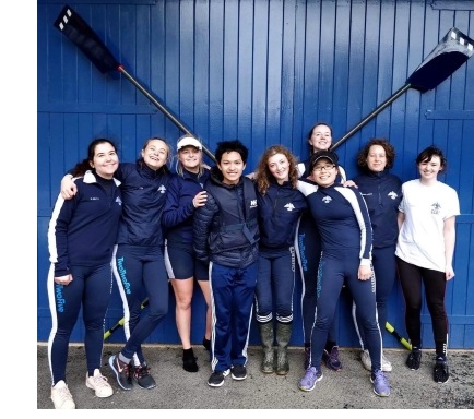 The crew of Christ's W1 boat, posing with their arms around each other outside in the front door of the Christ's boat house