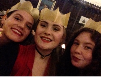 Three young women in gold paper crowns smiling at the camera.