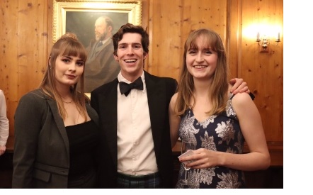 Two women (left and right) and a man (centre) in formal dress in the OCR at Christ's College, Cambridge.