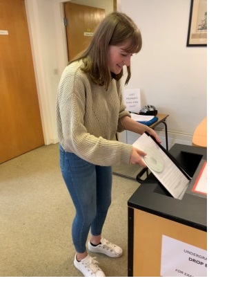 A female student handing in coursework at the Faculty of Music in Cambridge.