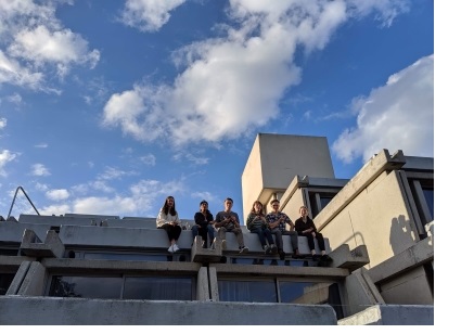 A shot from an upward-looking angle of six students sat on the 'typewriter building' in New Court at Christ's College, Cambridge.