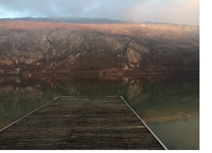 The view of a mountain from across a lake, at the end of a jetty.