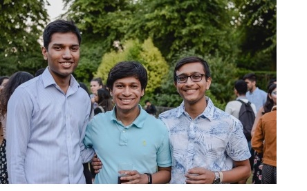 Three men posing for a photo together at a garden party in Cambridge