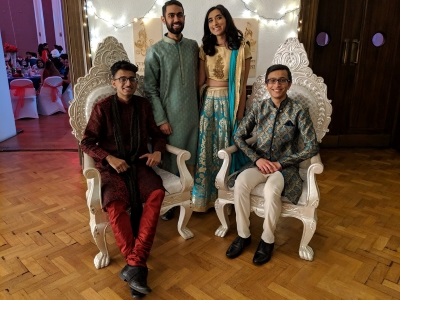 Four students, two sitting on ornate white chairs and two standing behind them, at an event organised by the Cambridge University India Society.