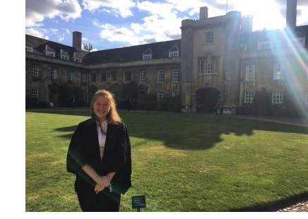 A young woman in an academic gown standing in First Court at Christ's College, Cambridge.