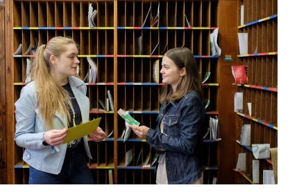 Two female students in the porters lodge of Christ's College, Cambridge.