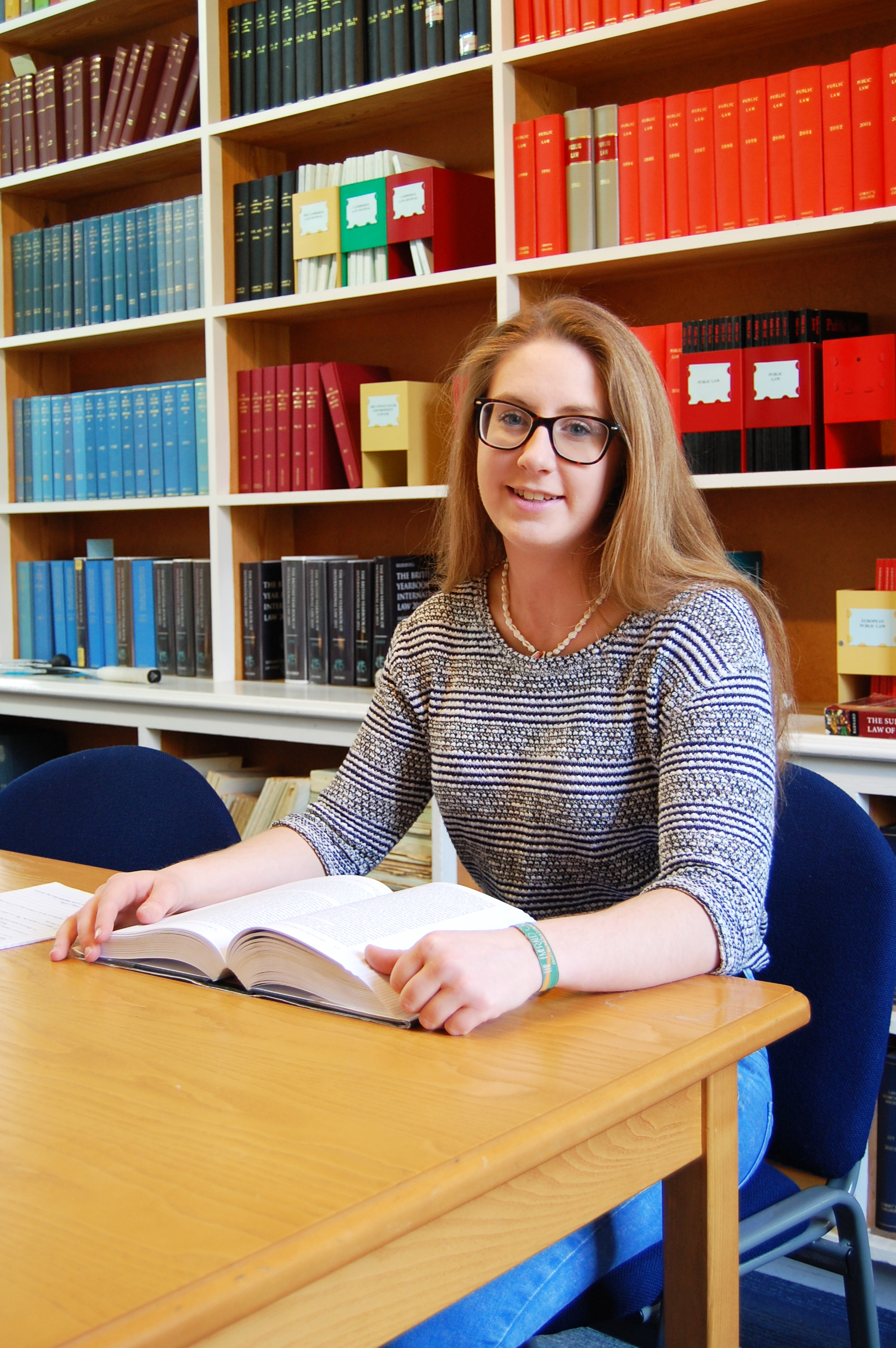 Female at desk with shelves of jounrals behind