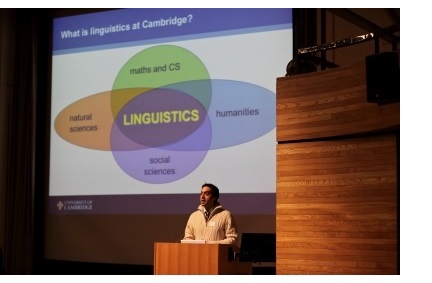A male lecturer giving a presentation on an MML open day at Cambridge. The slide projected behind him is entitled 'What is Linguistics at Cambridge?', and shows a diagram illustrating how Linguistics overlaps with Maths, Humanities, Social Sciences, and Natural Sciences.