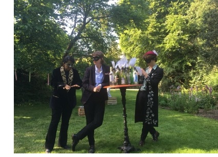 Three actors leaning on a table covered in bottles during a production of the 2019 May Week Shakespeare show at Christ's College, Cambridge - "Much Ado About Nothing".