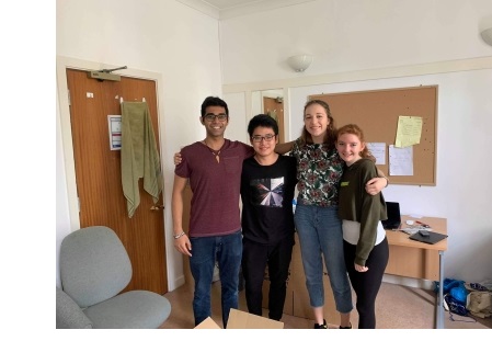 Four students, arms around each other, in a student room at Christ's College, Cambridge.