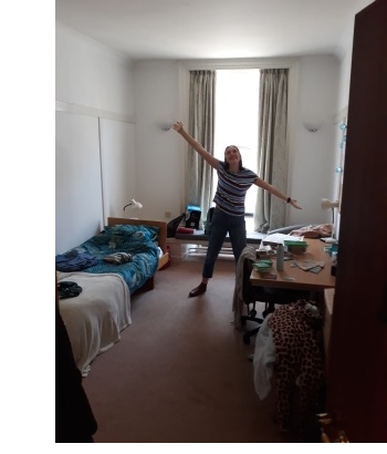 A young woman posing for a photo in a student room at Christ's College, Cambridge.