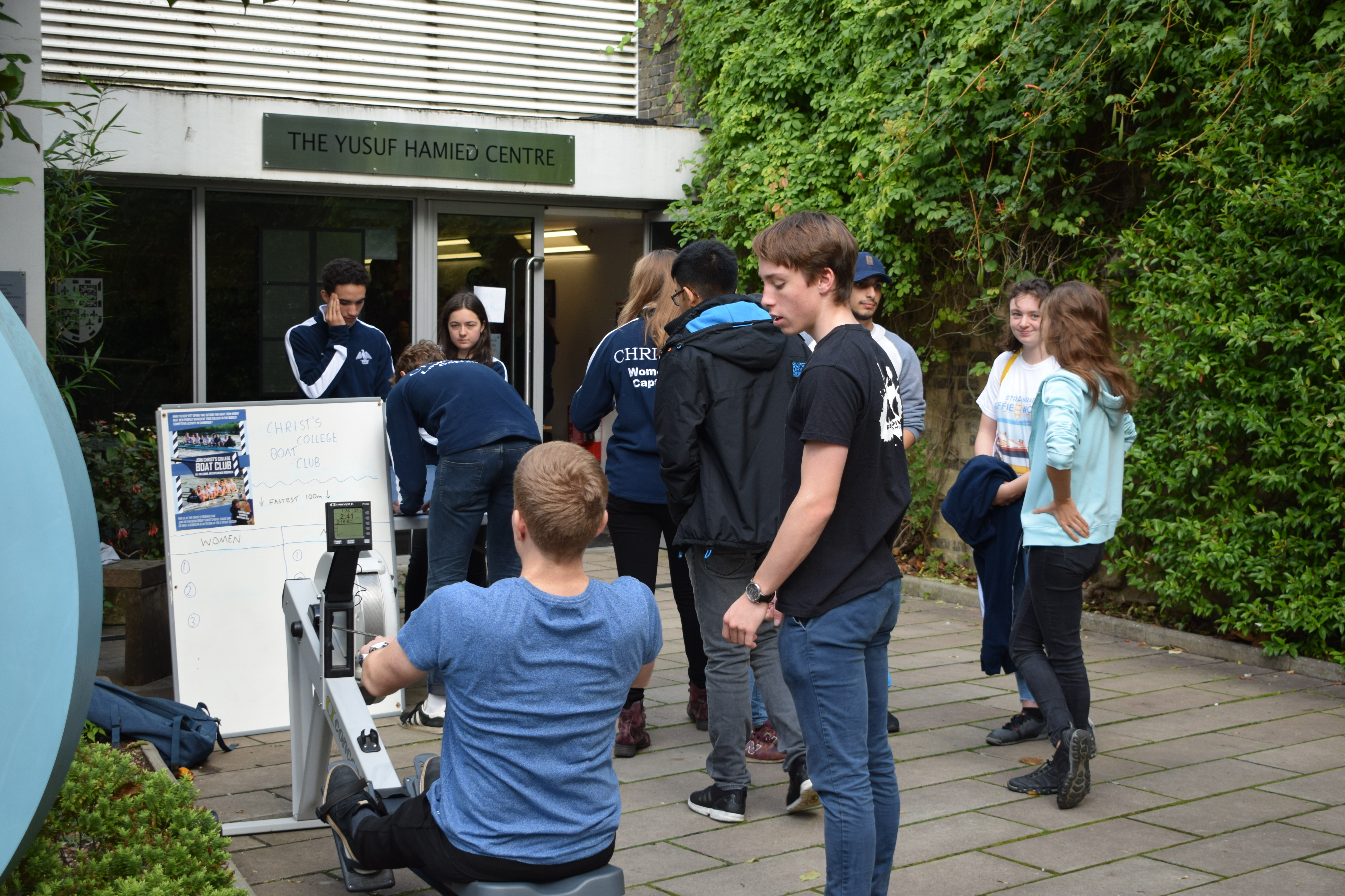 Group of students including one on a rowing machine