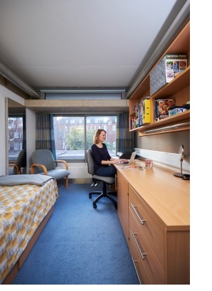 A woman sits with a laptop at a desk in a student room in New Court at Christ's College, Cambridge.