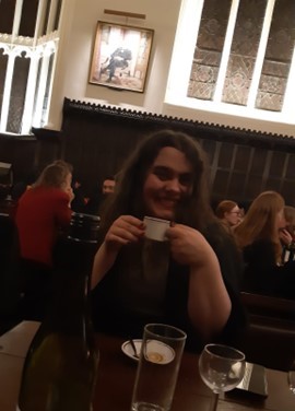 A student sits at a table in Formal Hall, holding a teacup