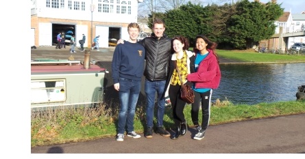 A group of students stood by a boat on the River Cam