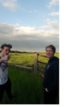 Two men, smiling at the camera, stood in the entrance to a field.