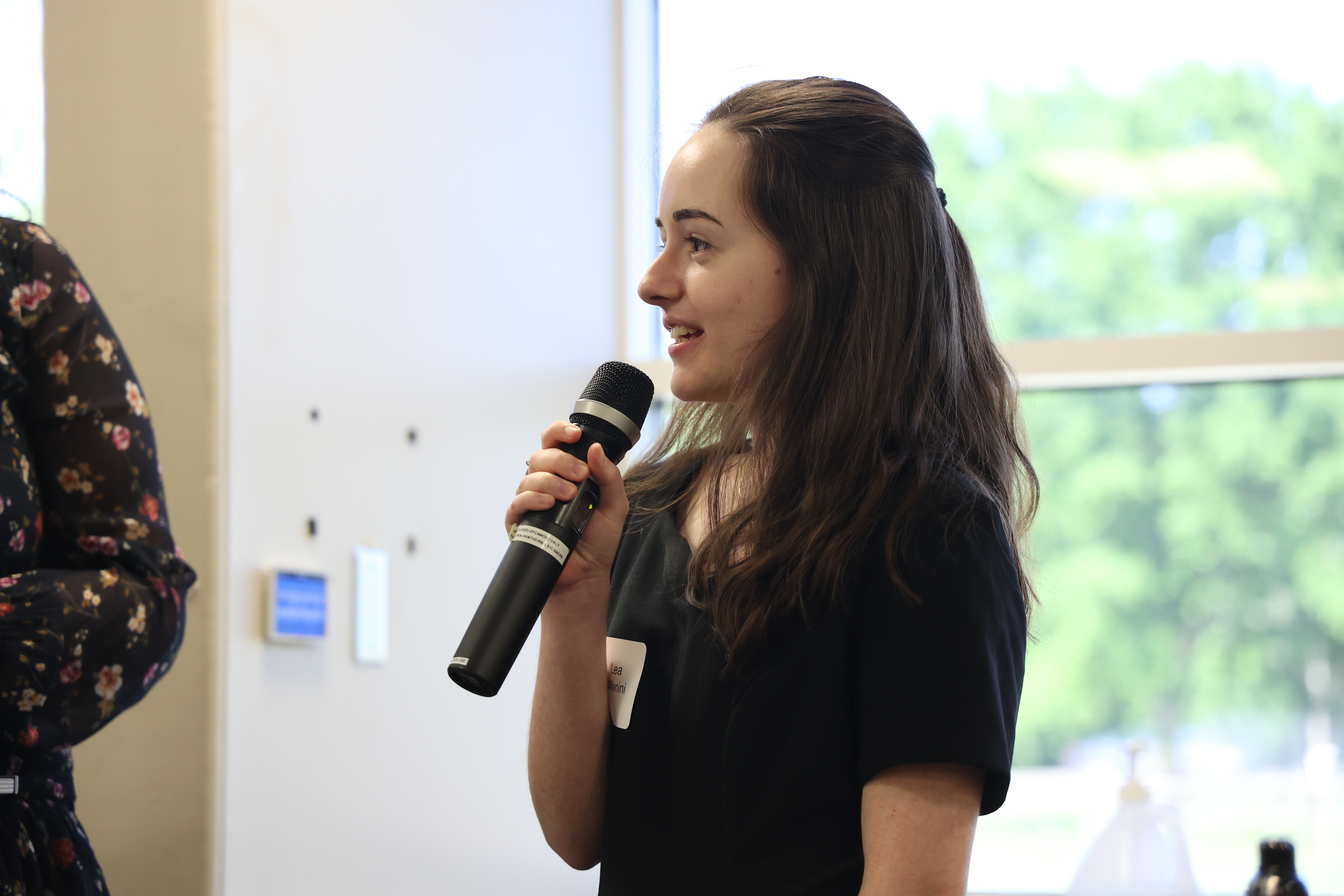 Headshot of Lea speaking with a microphone