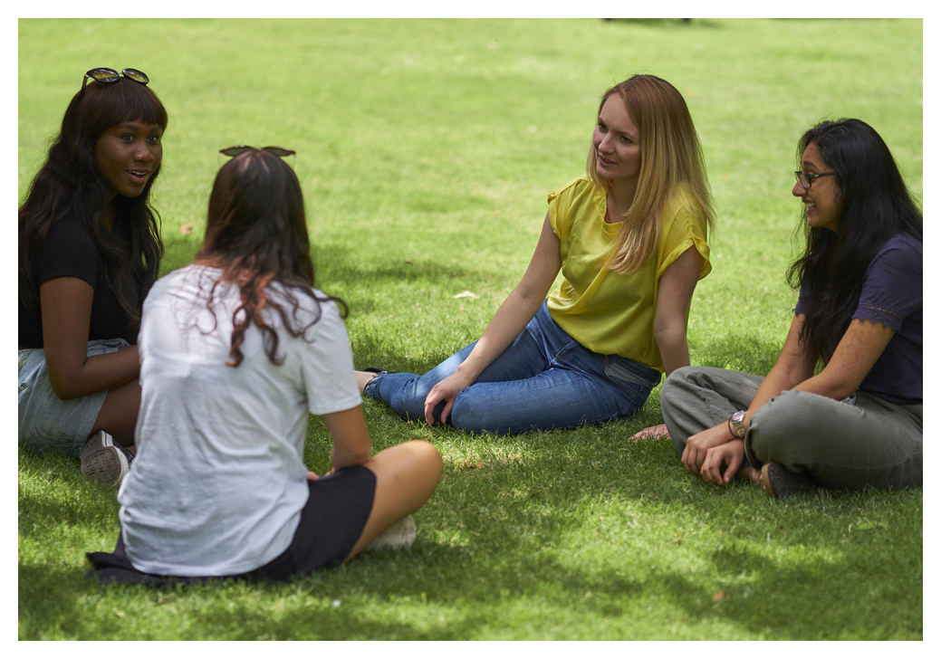 Students chatting, sat on grass