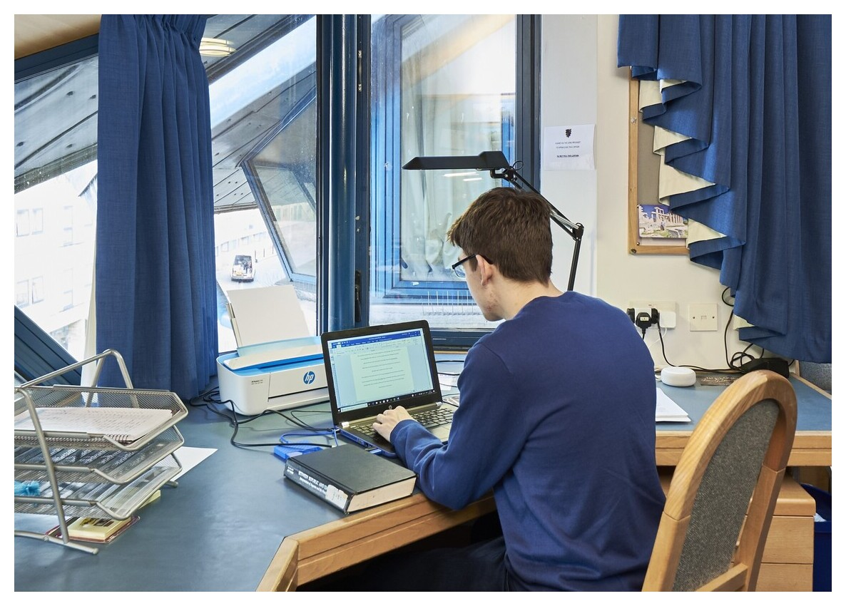 Student working at desk in front of window