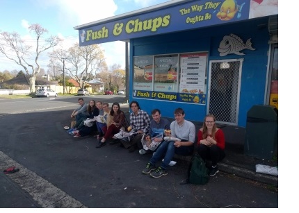 A group of students sat outside a fish and chips shop.