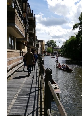 A walkway by the River Cam in Cambridge, with punts on the river.