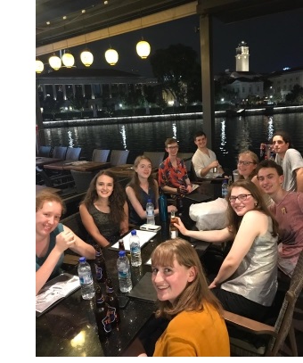 A group of young men and women at a table in a restaurant.